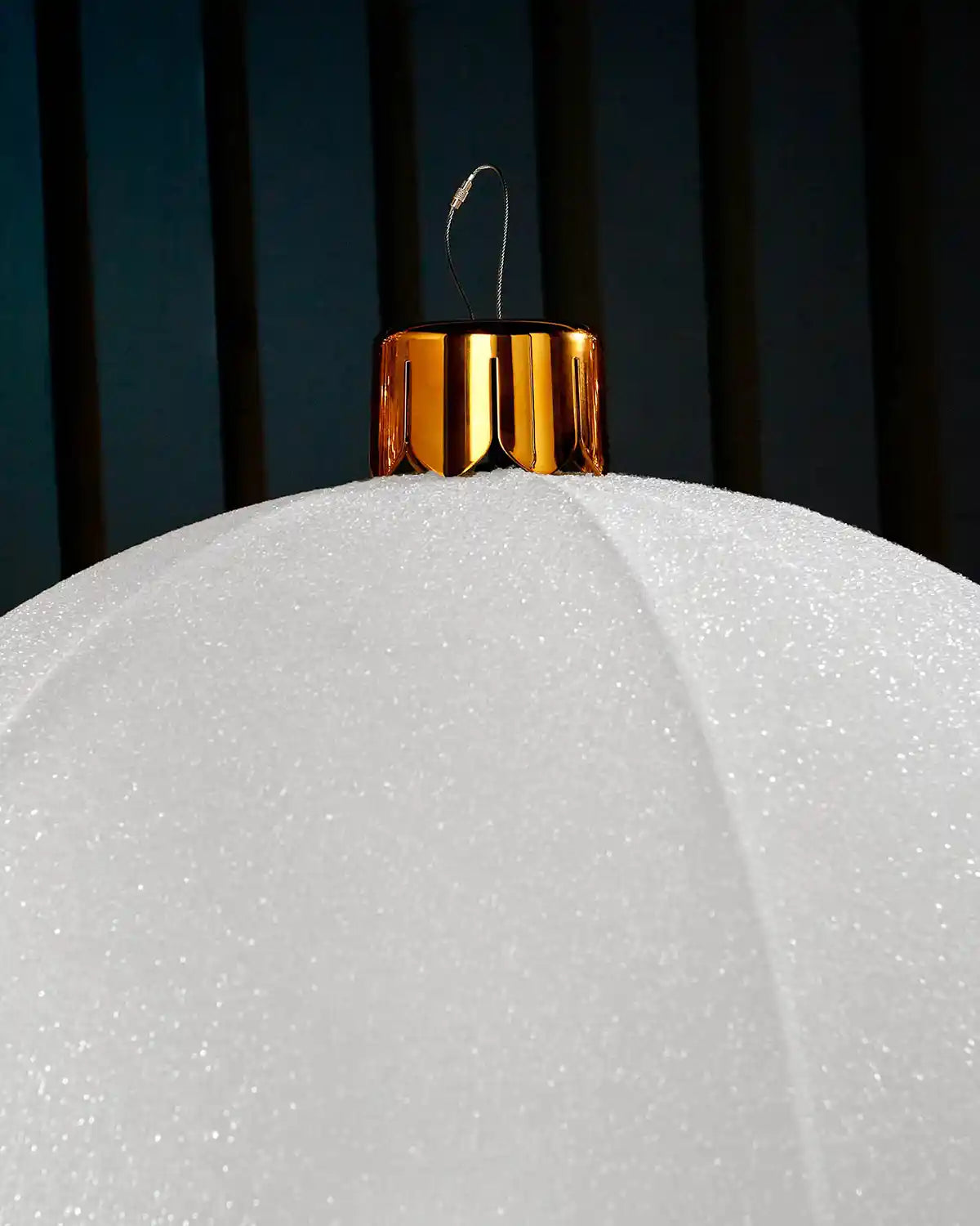 Close-up of the gold cap and hanging wire on a white inflatable tinsel Christmas bauble.