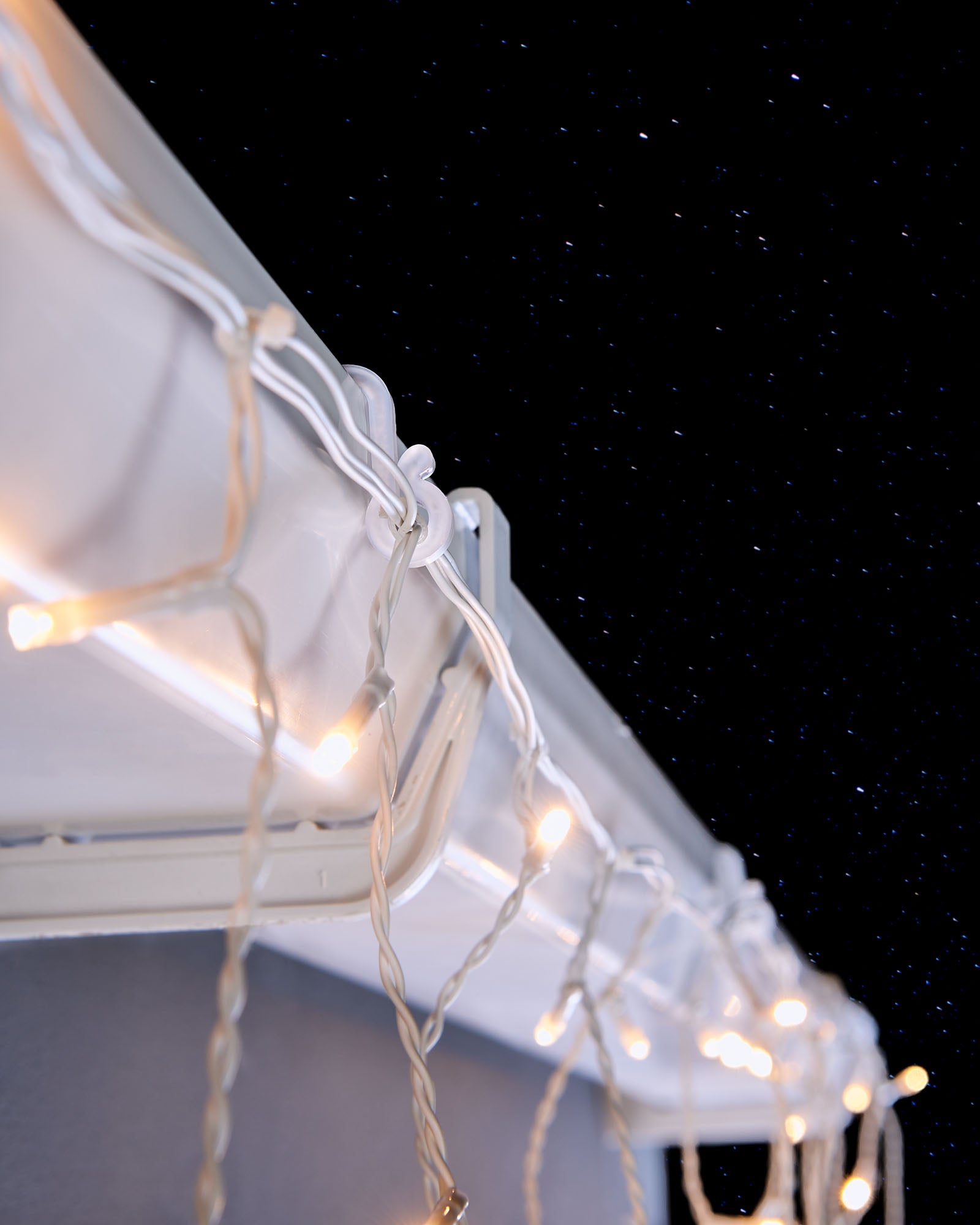 White mini gutter hooks securing warm white Christmas lights along guttering