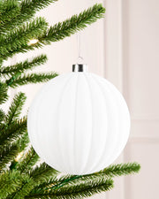 15 cm white oversized velvet ribbed bauble hanging from a Christmas tree with a silver cap.