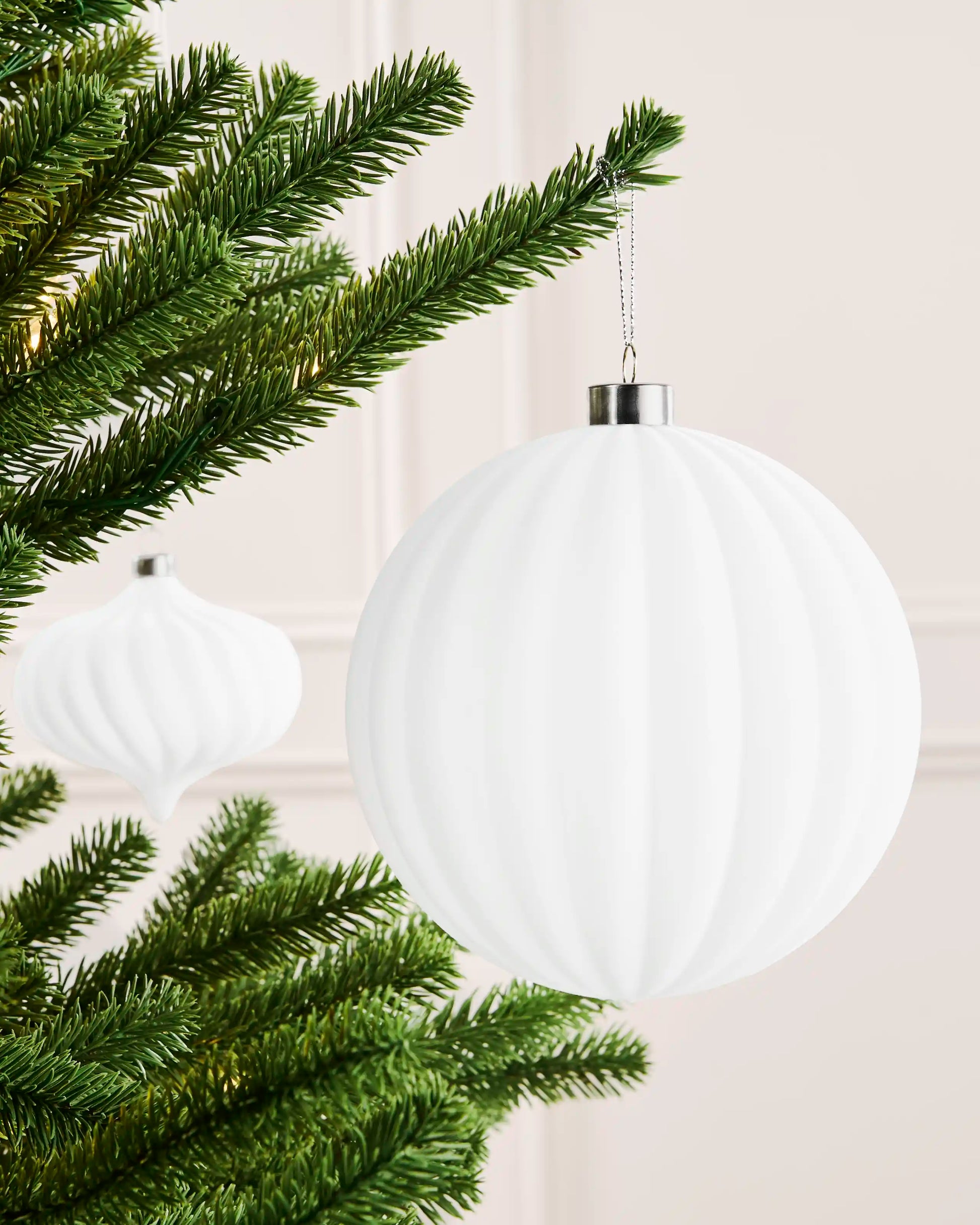 White 15 cm oversized velvet ribbed bauble displayed on a Christmas tree with silver hanging string.