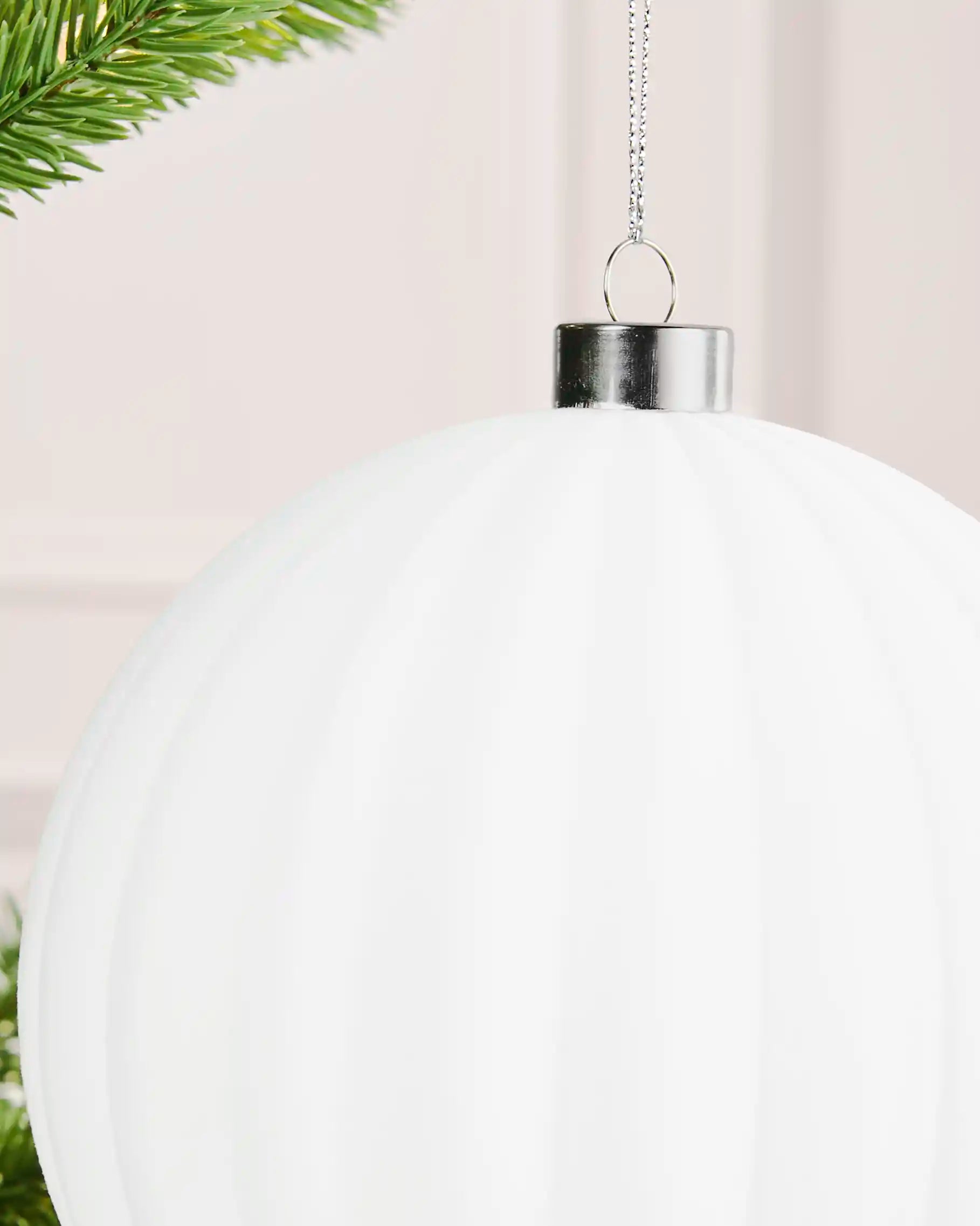 Close-up of a white 15 cm oversized velvet bauble showing its ribbed surface and silver cap.