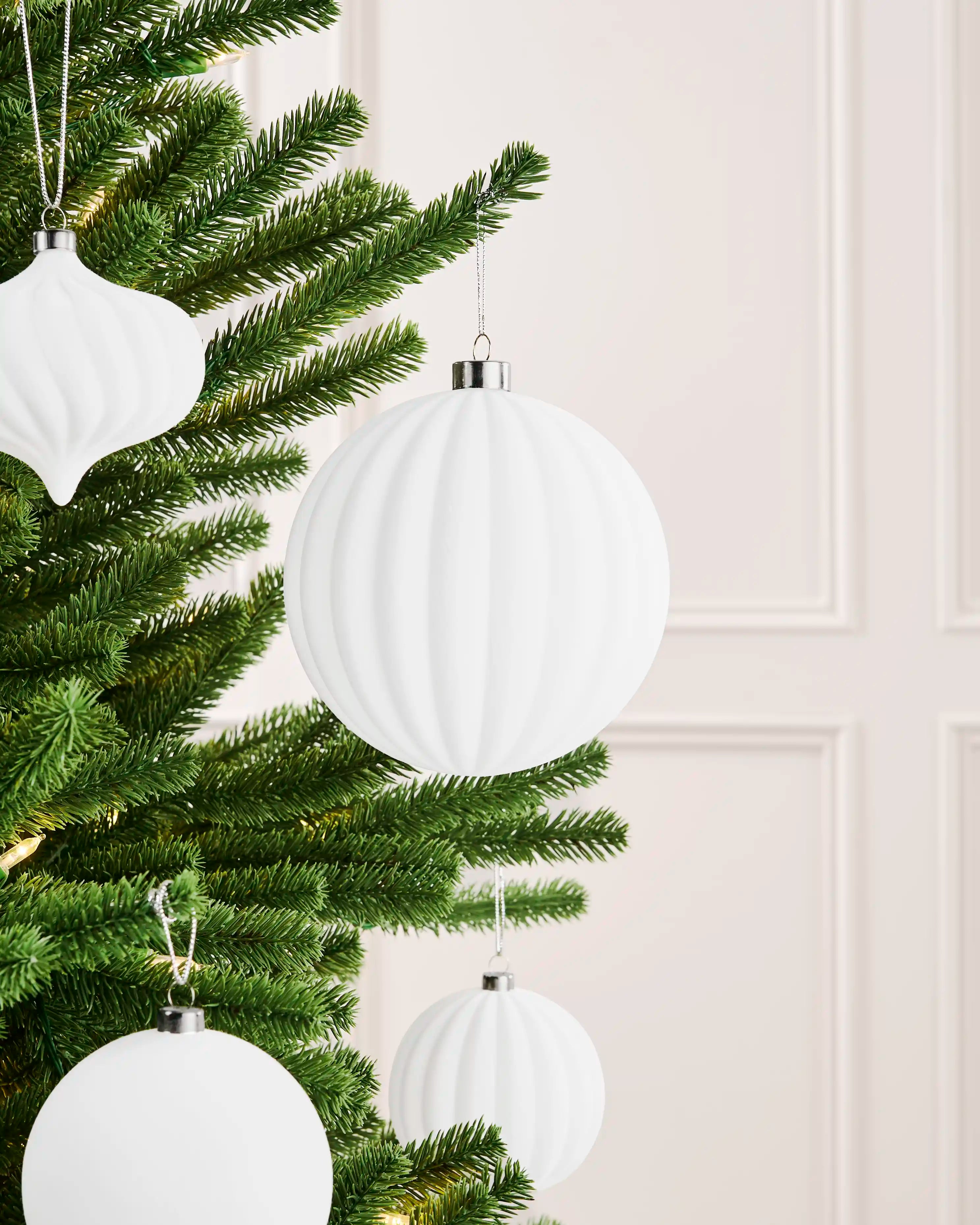 Oversized 15 cm white velvet ribbed bauble styled on a Christmas tree with coordinating white ornaments.
