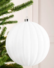 20 cm white oversized velvet ribbed bauble hanging from a Christmas tree with a silver cap and silver hanging string.