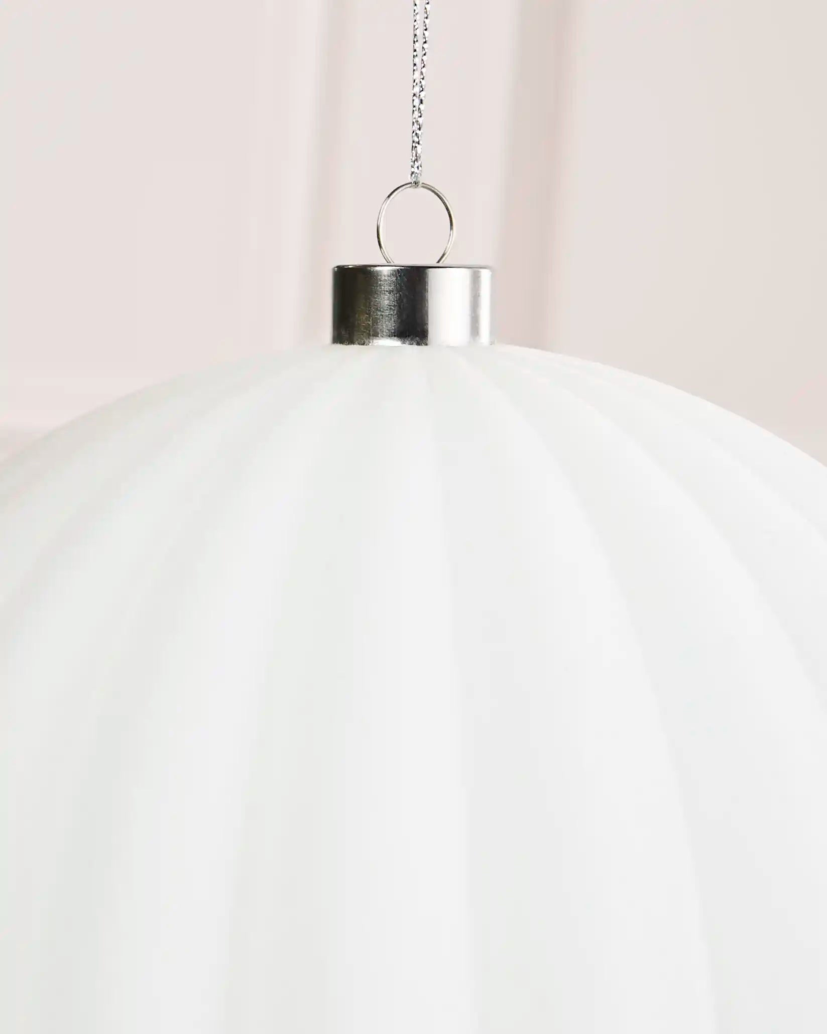 Close-up of a 20 cm white velvet ribbed bauble showing its ribbed texture and silver hanging cap.