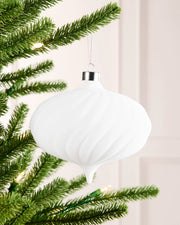 15 cm white oversized velvet spiral ribbed bauble hanging from a Christmas tree with a silver cap and silver hanging string.