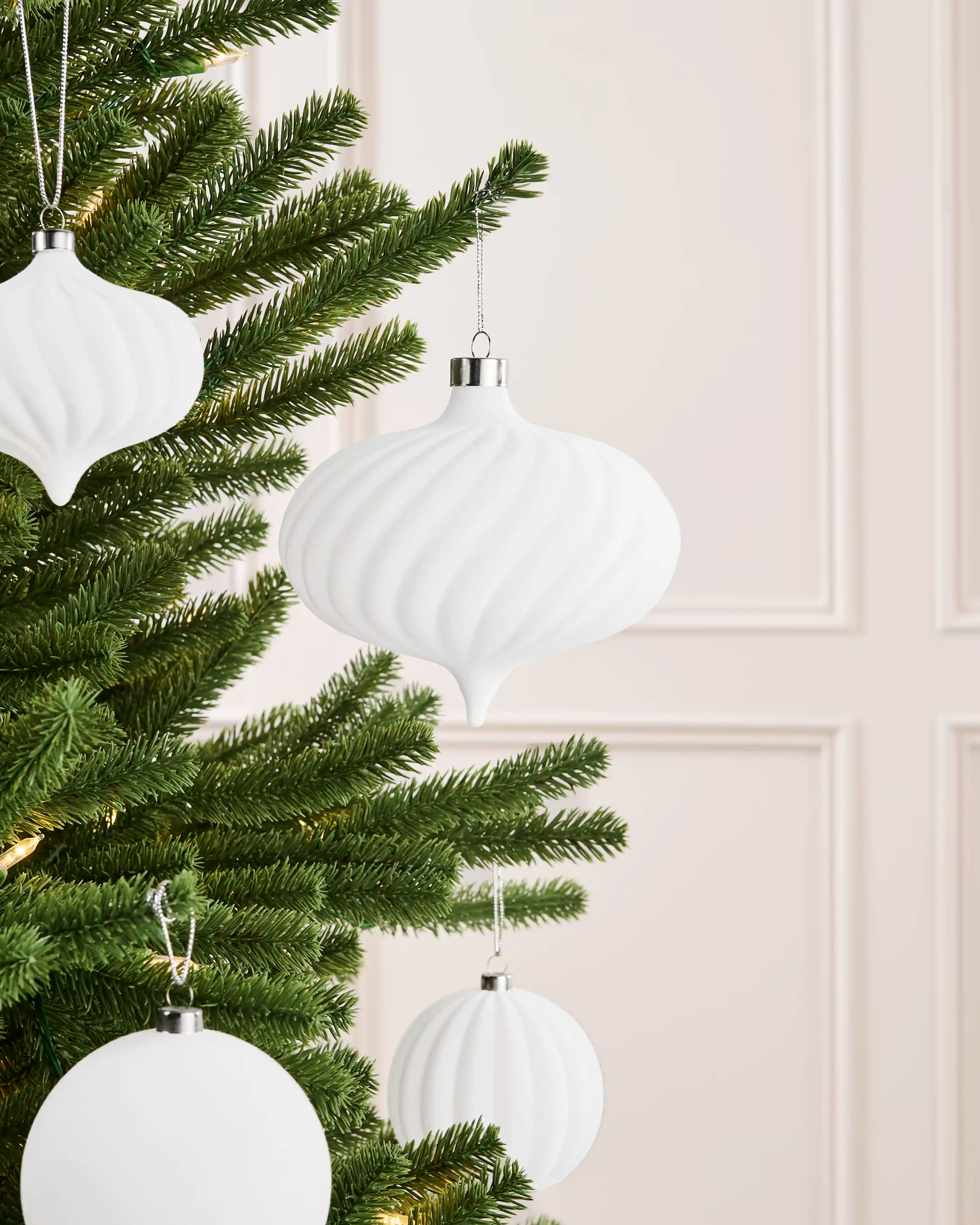 Oversized 15 cm white velvet spiral ribbed bauble styled on a Christmas tree with coordinating white baubles.