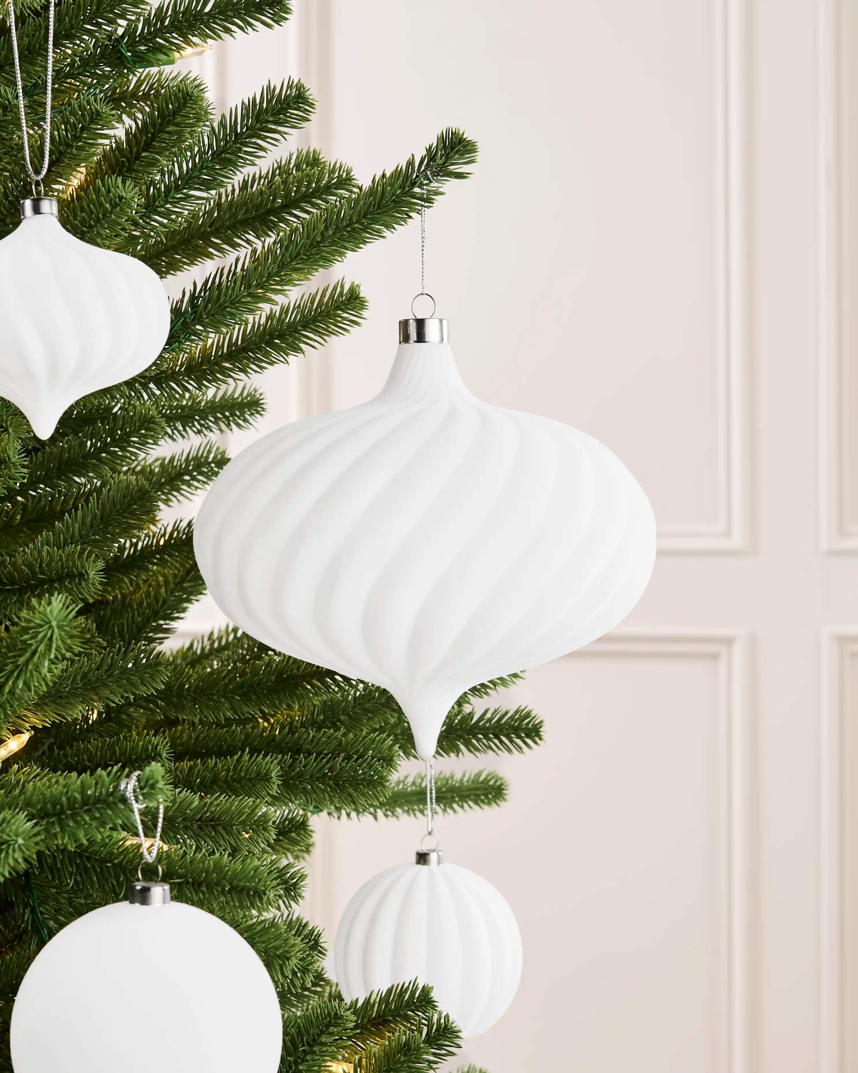 Oversized 20 cm white velvet spiral ribbed bauble styled on a Christmas tree with coordinating white baubles.