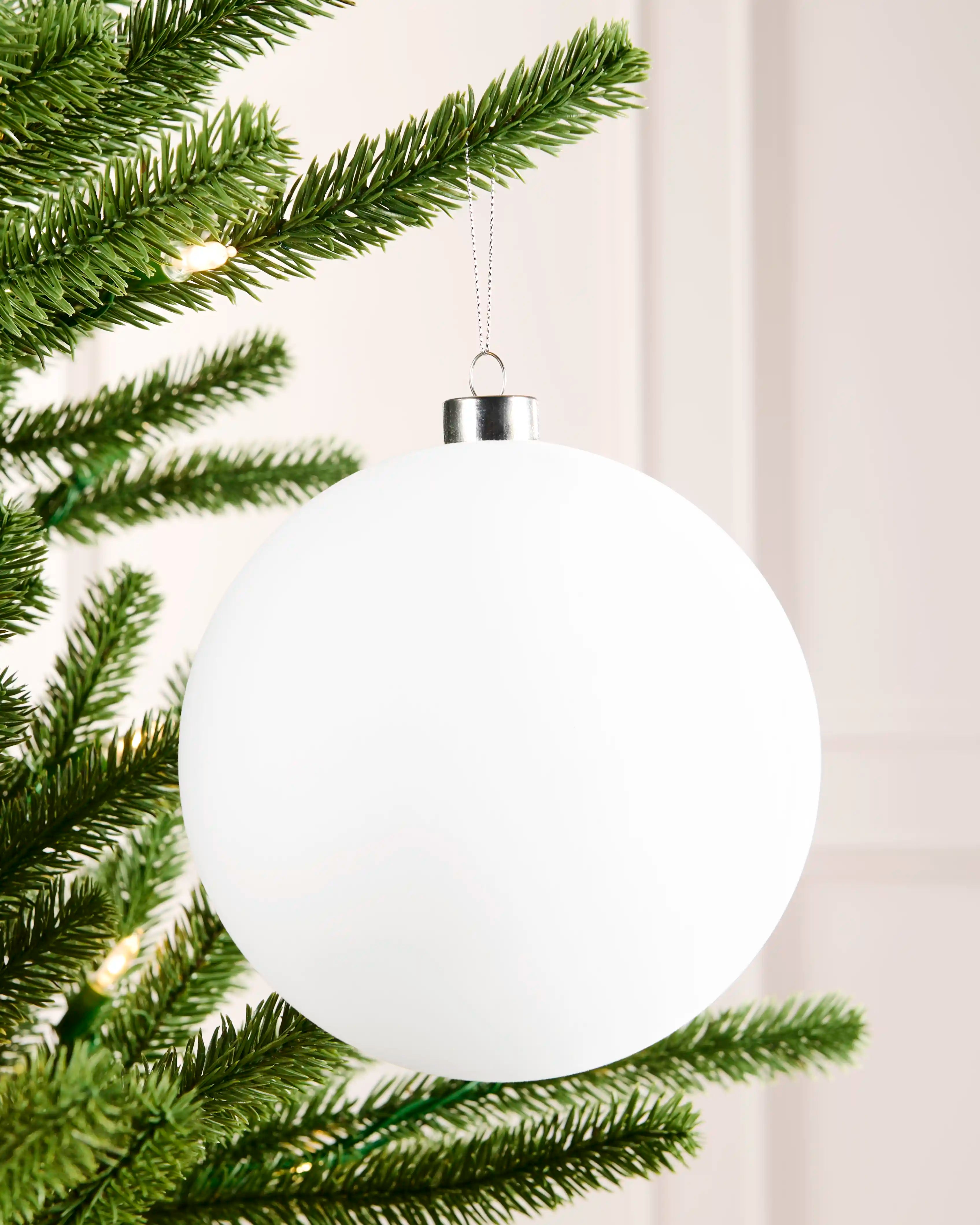 15 cm white oversized velvet traditional bauble hanging from a Christmas tree with a smooth round finish.