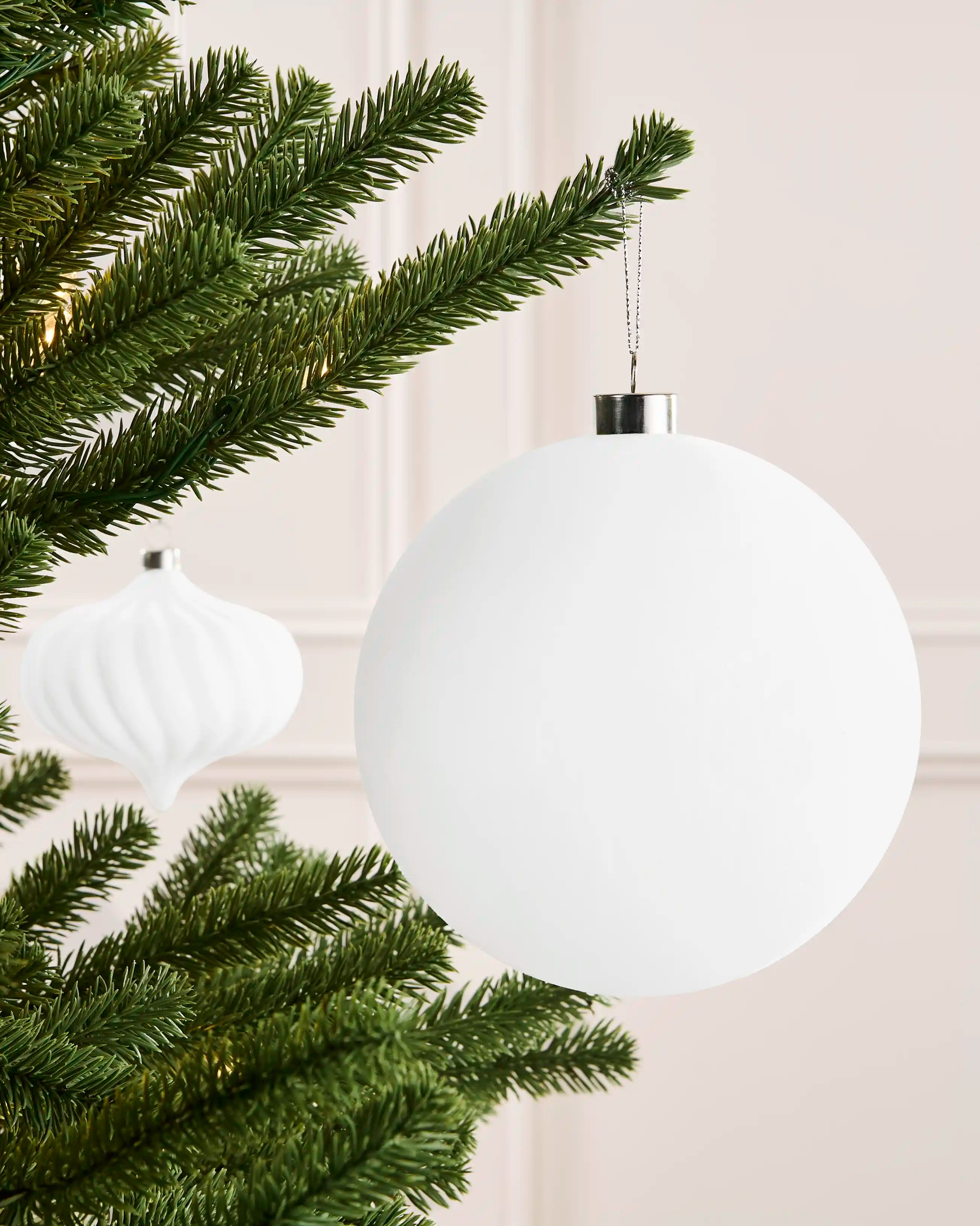 White 15 cm oversized velvet traditional bauble displayed on a Christmas tree with a silver hanging cap.