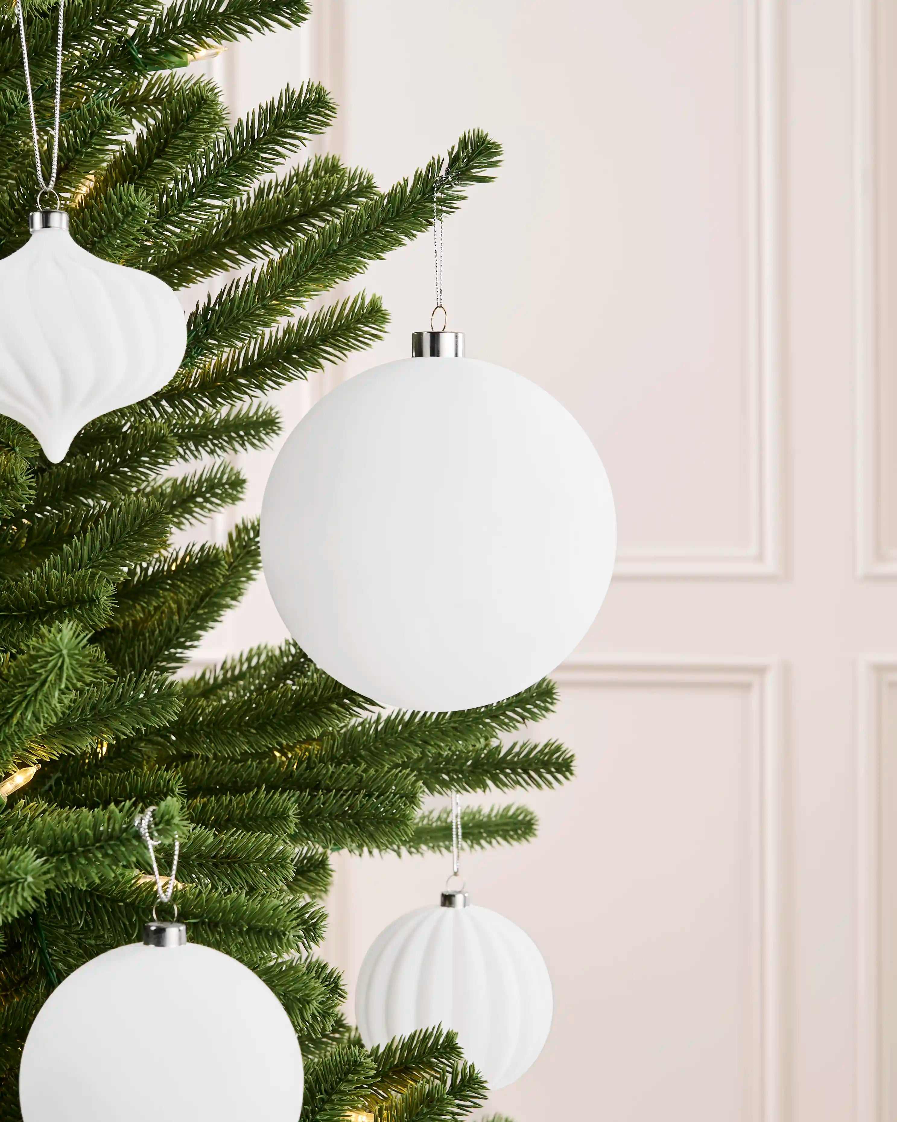Oversized 15 cm white velvet traditional bauble styled on a Christmas tree with coordinating white ornaments.
