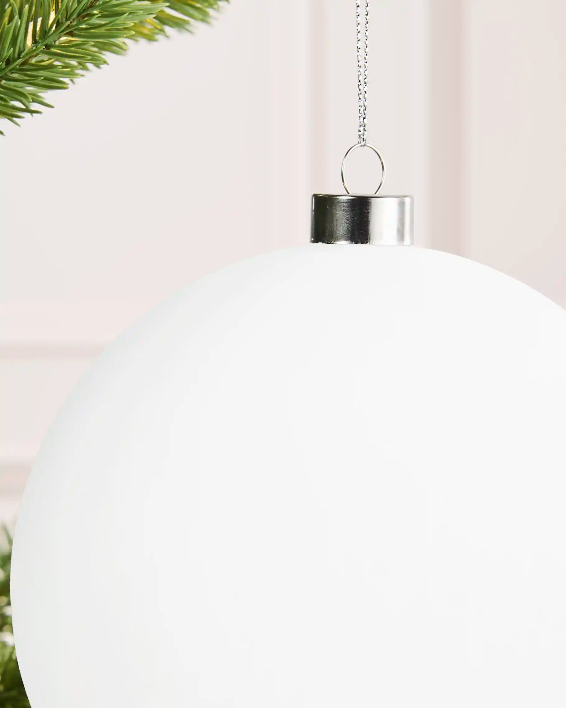 Close-up of a white 15 cm oversized velvet bauble showing its smooth finish and silver cap.