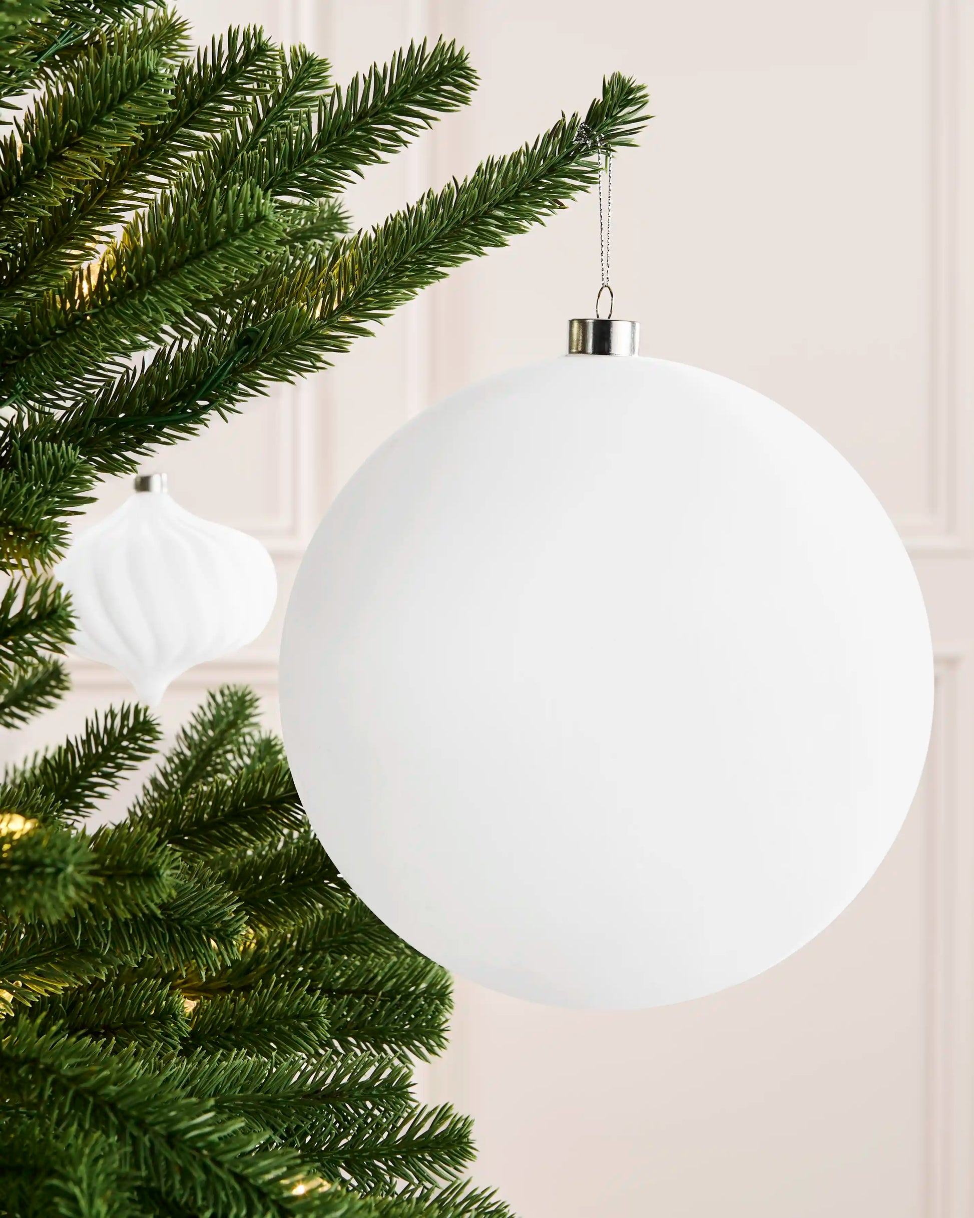 White 20 cm traditional velvet bauble hanging from a Christmas tree, showing its smooth rounded profile and silver cap.