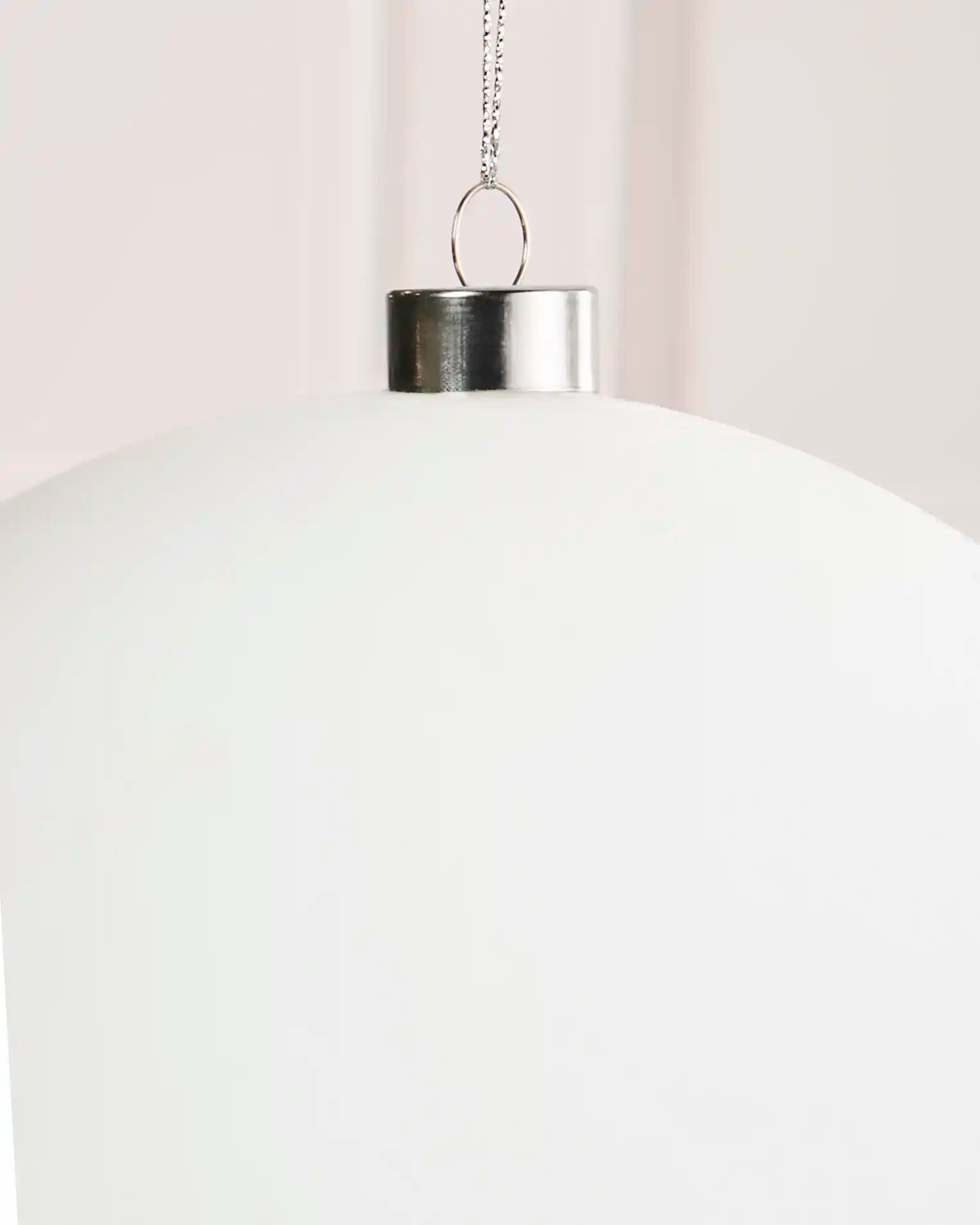 Close-up of the smooth white velvet finish, silver metal cap and hanging string on the 20 cm bauble.