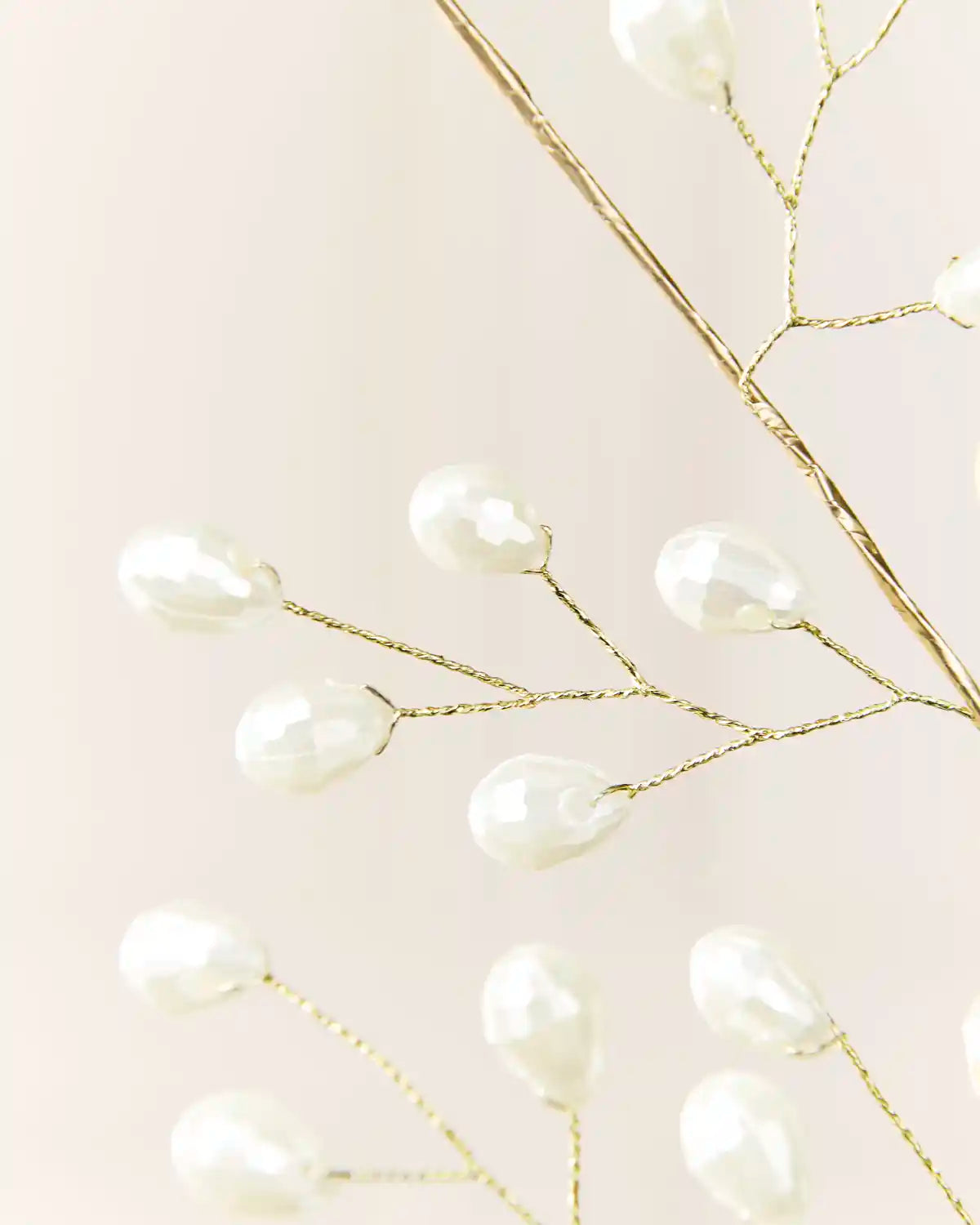 Detailed view of white faceted pearl beads spaced along fine gold-toned wire branches.