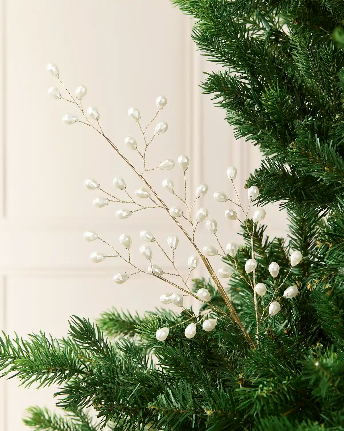 68 cm white pearl beaded Christmas tree pick arranged among green Christmas tree branches.