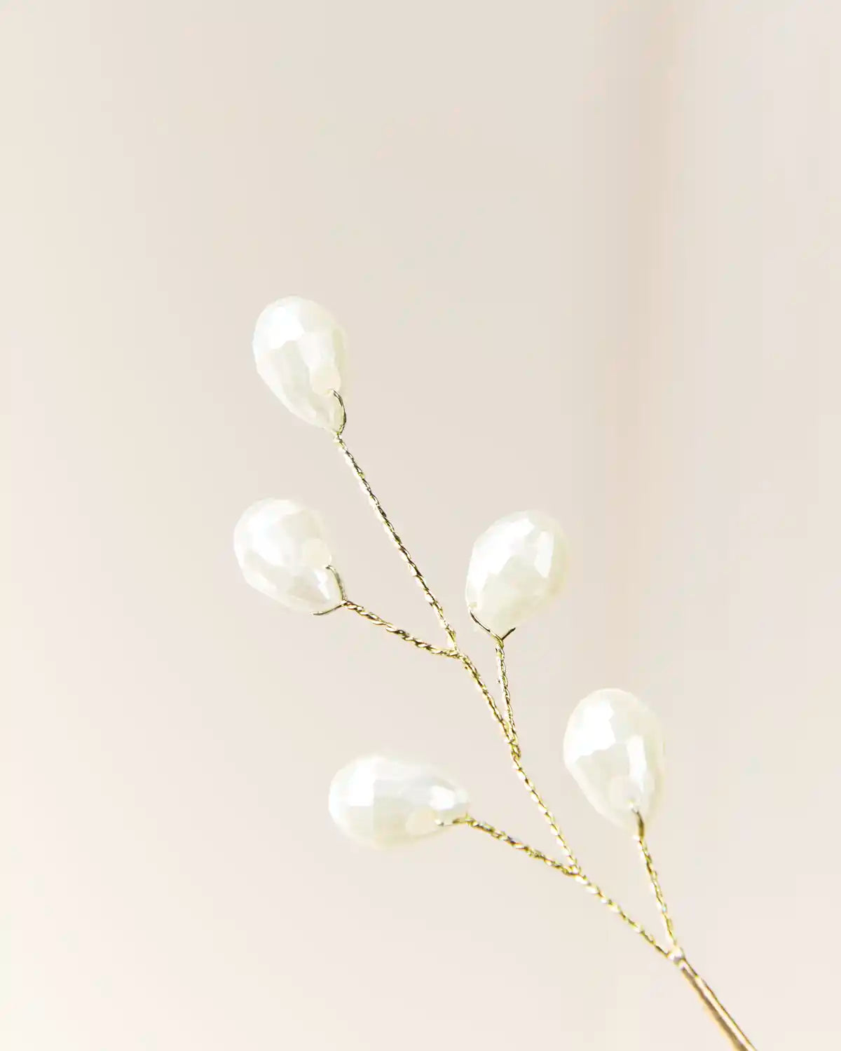 Close-up of the upper branch tips with white teardrop pearl beads on twisted wire stems.