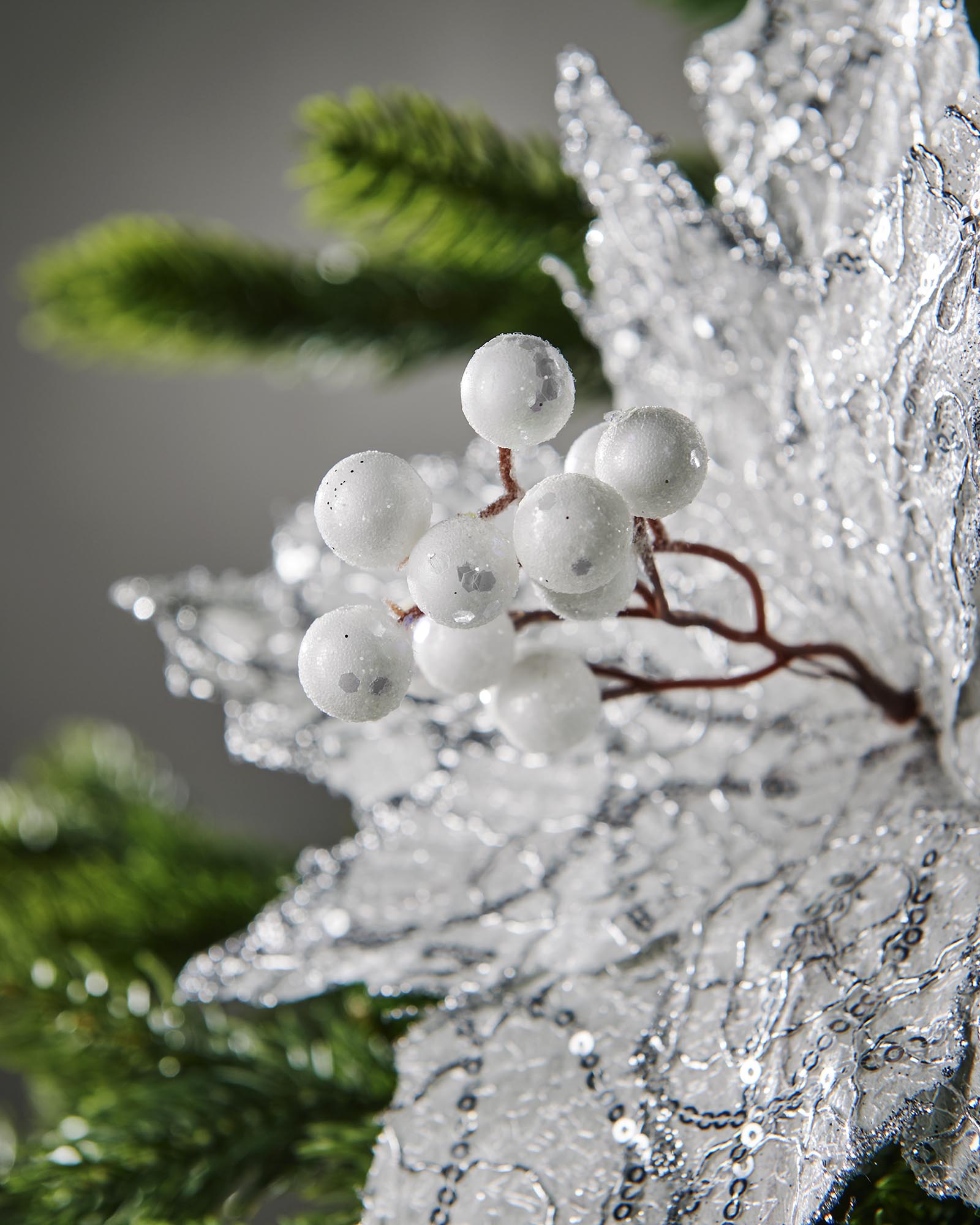 White sequin poinsettia flower displayed on Christmas tree