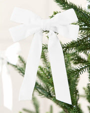 White 16.5 cm velvet double bow with long tails attached to a Christmas tree branch.