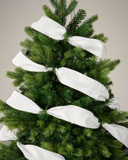 White velvet ribbon wrapped around a Christmas tree as a soft festive decoration.