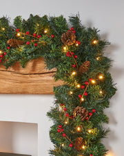 A close-up of a pre-lit mixed pine garland with pinecones and berries, featuring warm white LED lights.