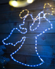 An angel silhouette created by a rope light with warm white and yellow LED lights against a wooden backdrop.