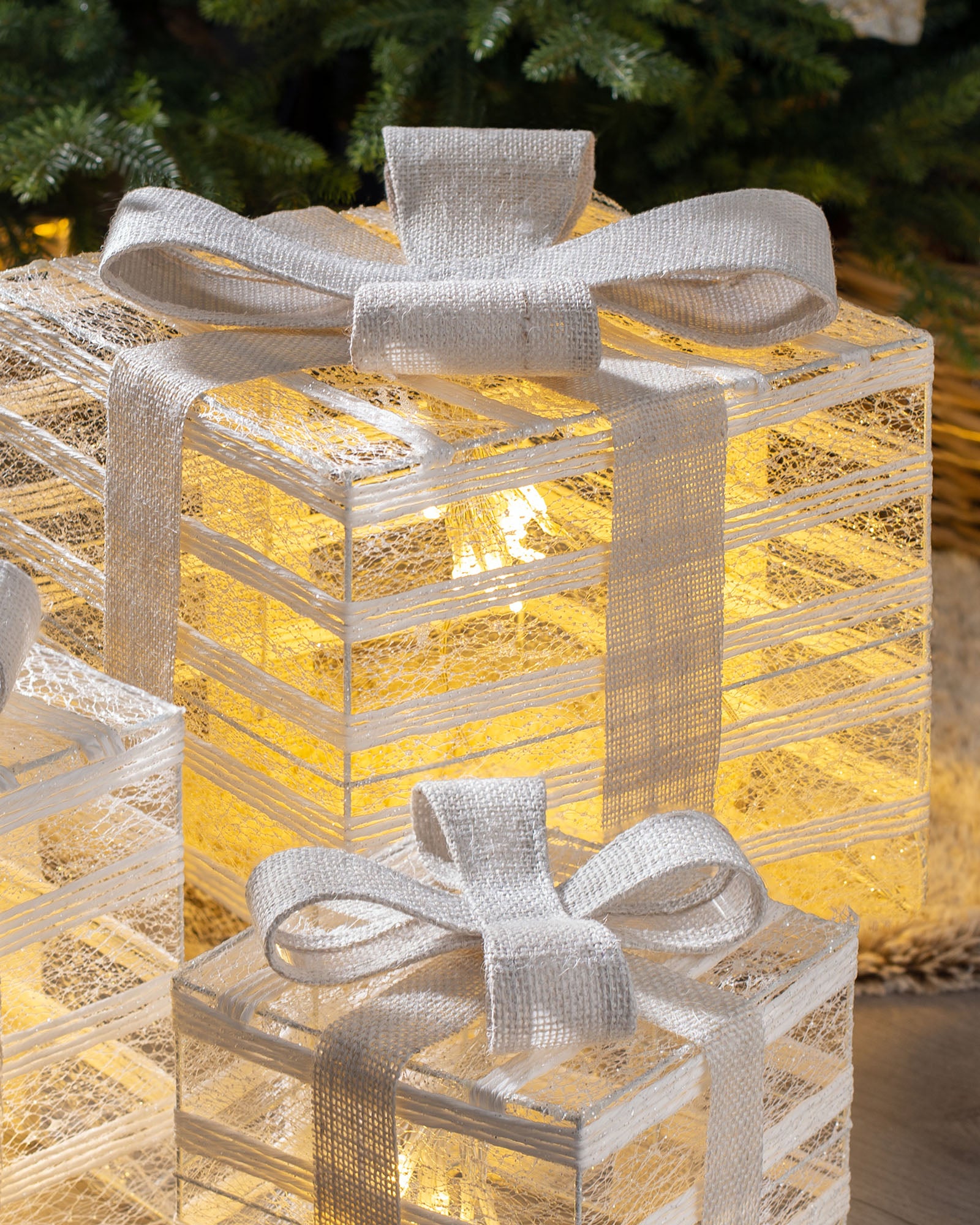 Close-up of pre-lit Christmas gift boxes with white ribbon bows and warm white LEDs