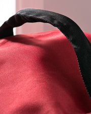 A red, waterproof storage bag for garlands and wreaths, displayed beside a festive Christmas wreath.