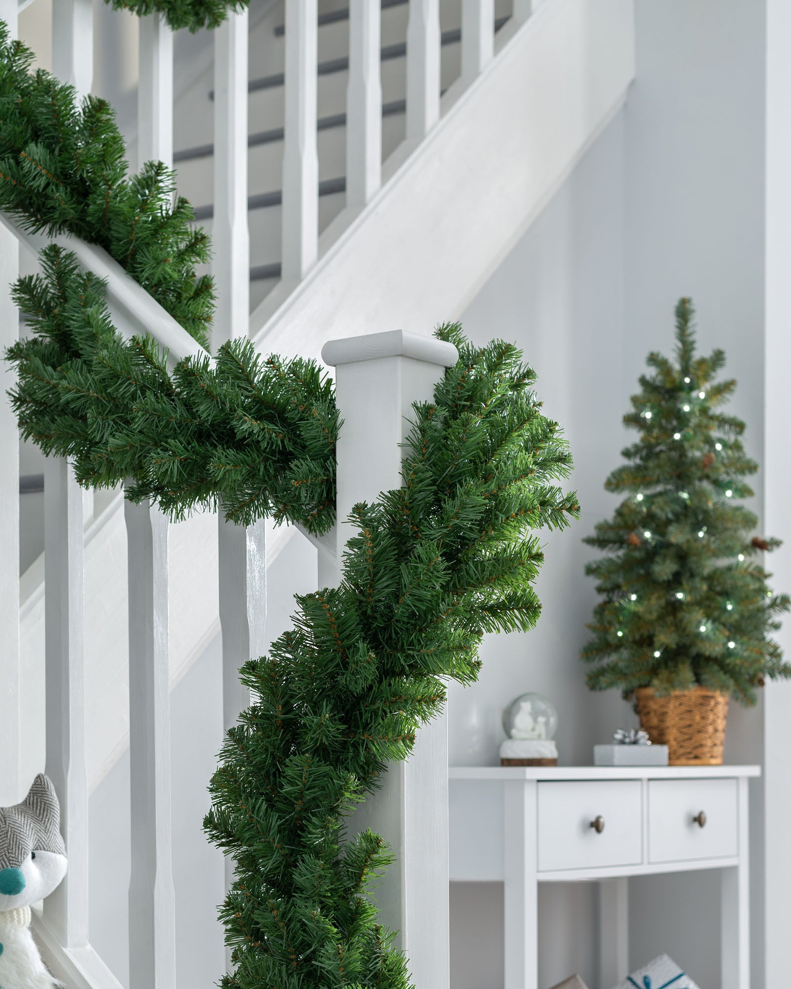 9ft extra thick pine Christmas garland displayed around a white staircase banister