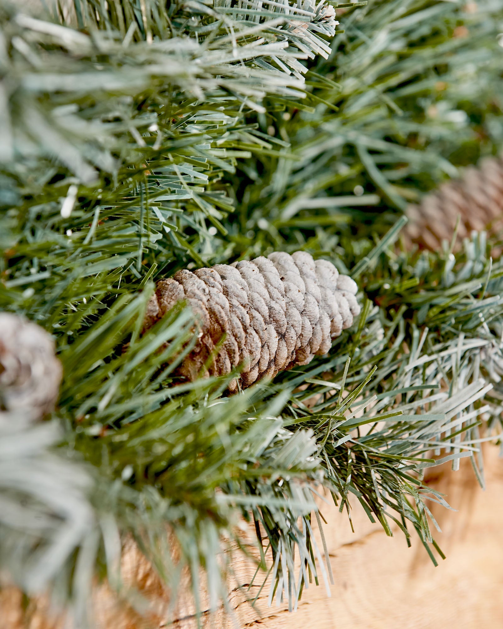 Close-up of a frosted pinecone nestled in a 9 ft blue spruce garland
