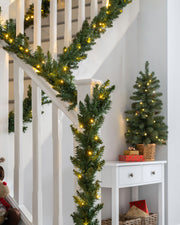 An 18 ft green garland with warm white LED lights displayed around a staircase Banister.