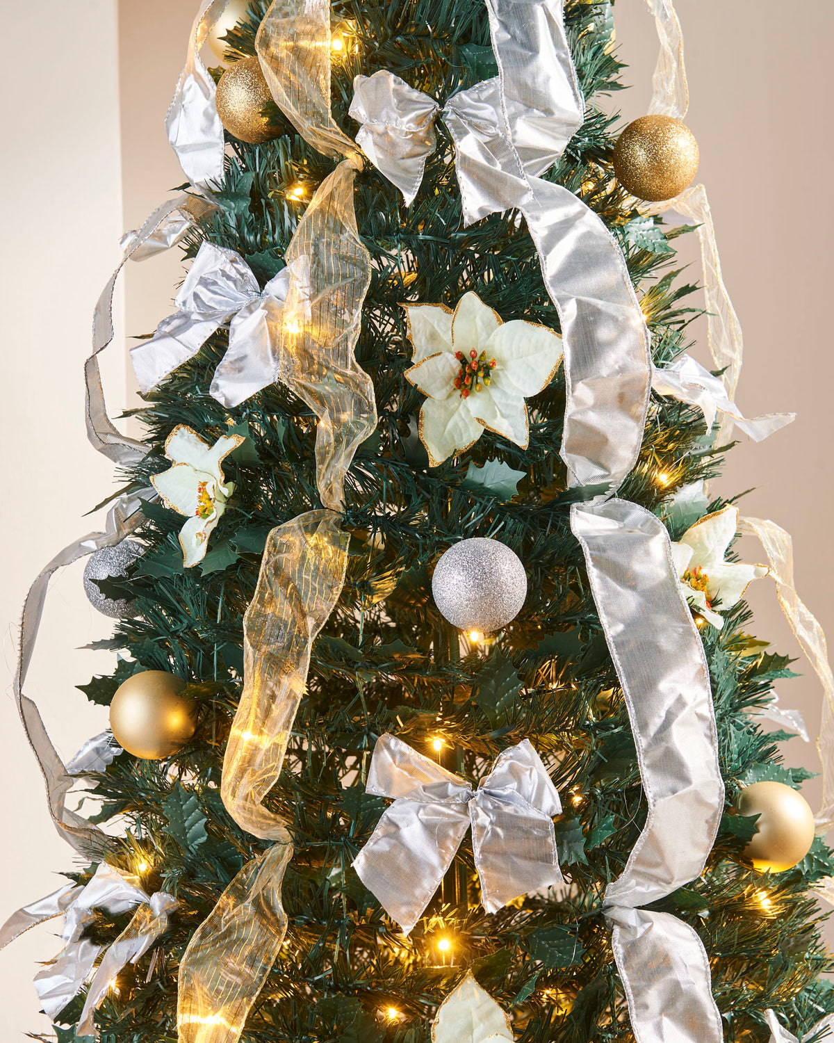 Pre-lit 6 ft decorated Holly Pop-Up Christmas tree with 150 warm white LEDs, champagne and silver baubles, poinsettias, and ribbons—easy setup, elegant festive centerpiece in a living room.