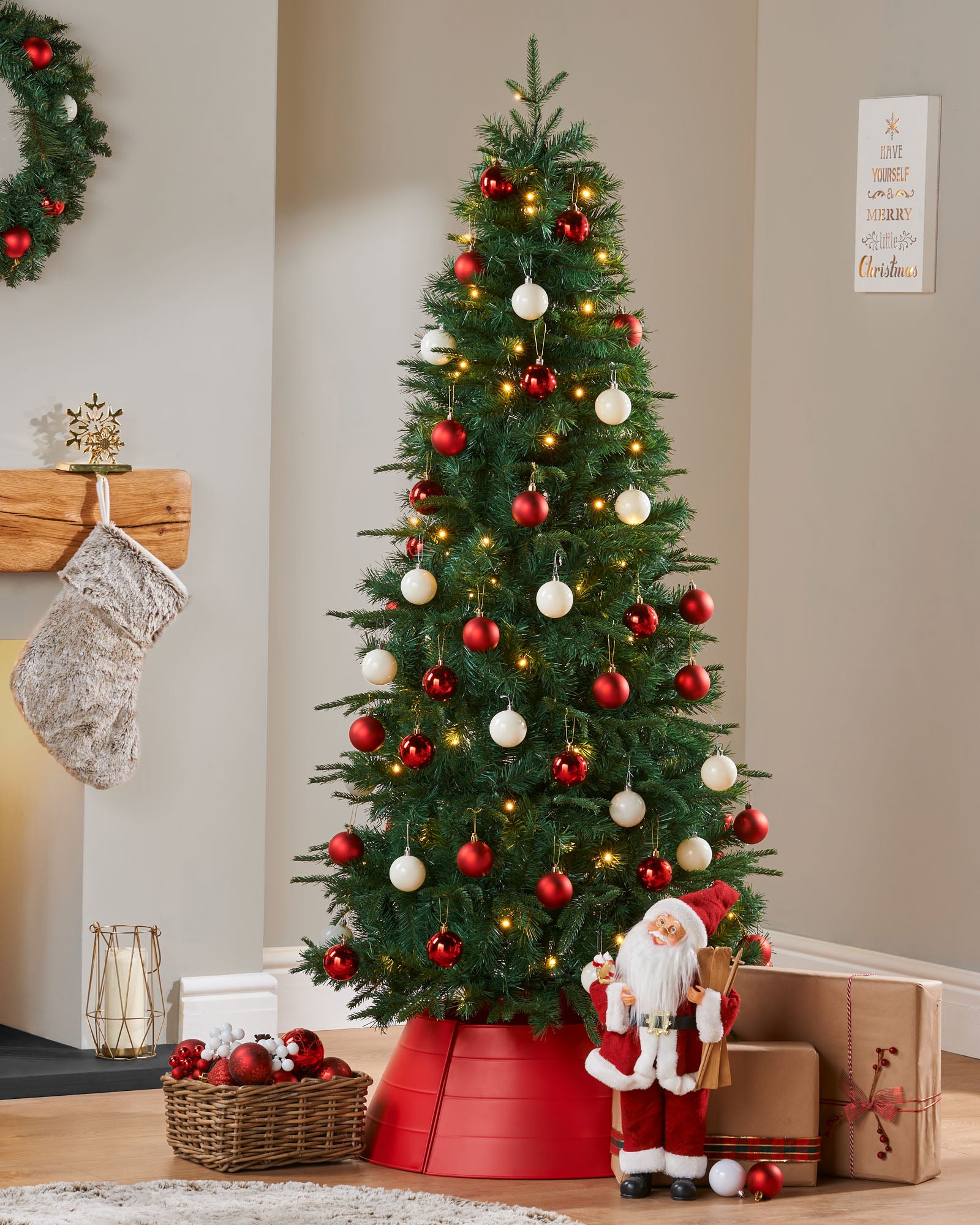 A pre-lit decorated pop-up Christmas tree with red and white baubles and integrated warm white LED lights, standing in a living room setting.