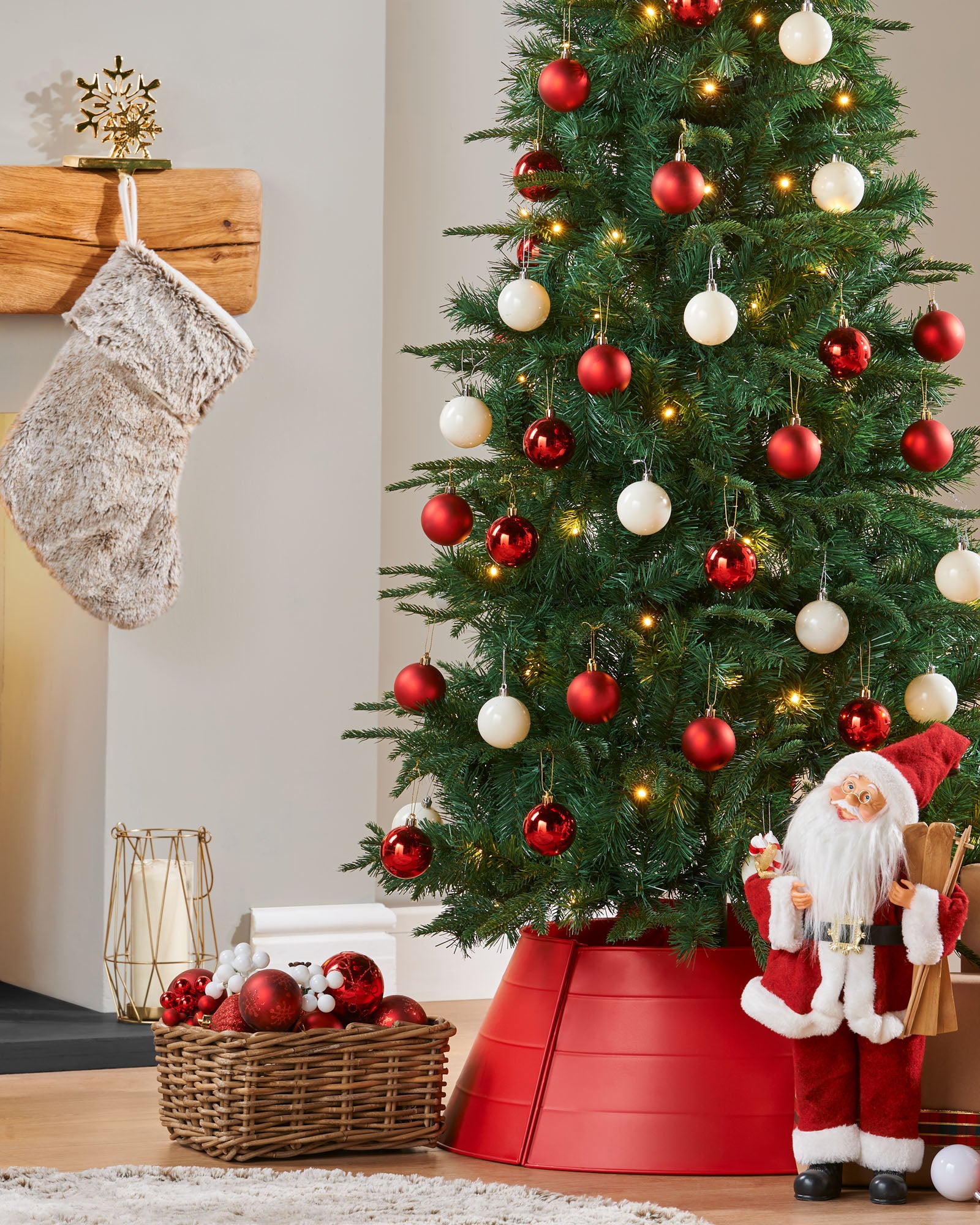 A pre-lit decorated pop-up Christmas tree with red and white baubles and integrated warm white LED lights, standing in a living room setting.