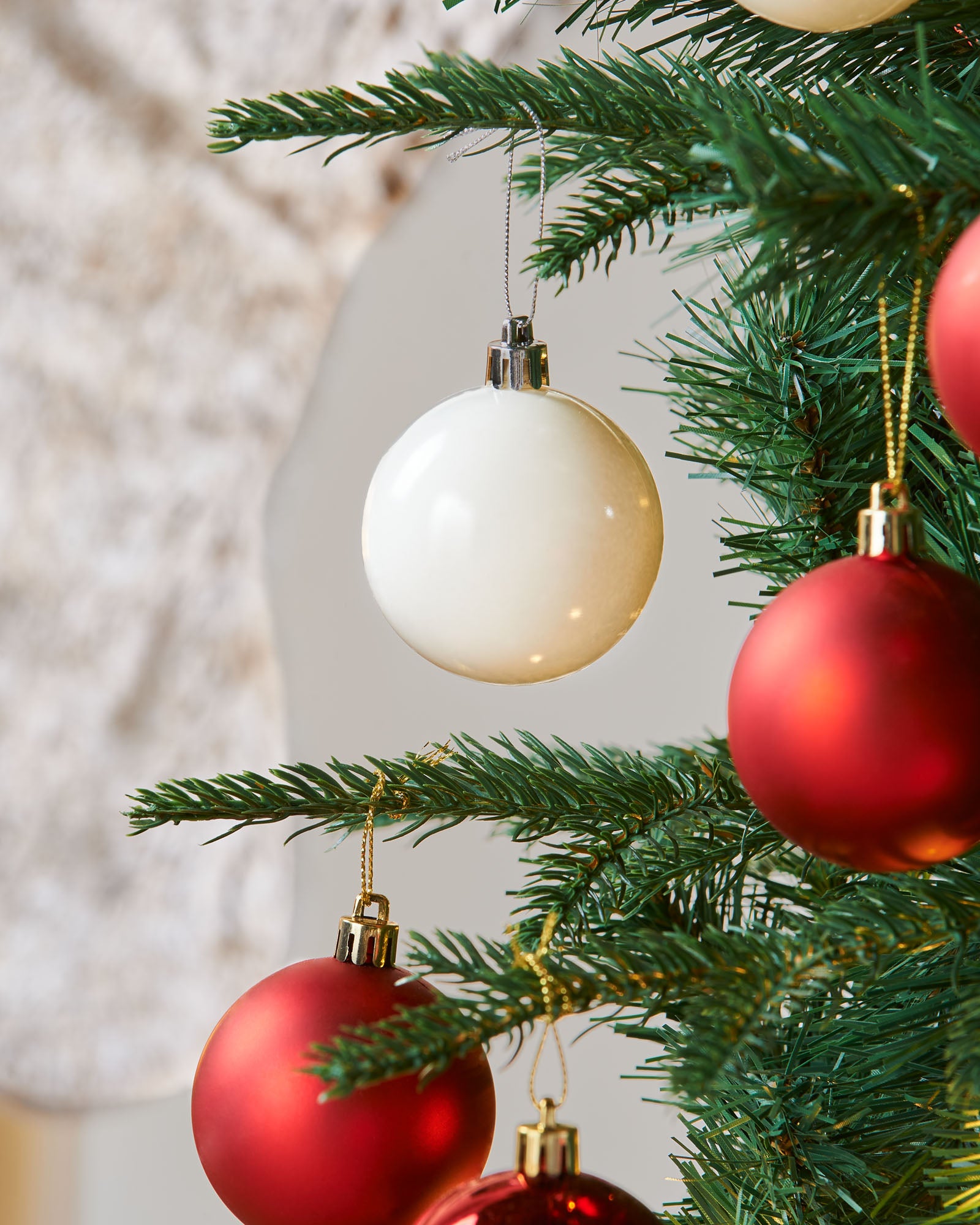 A pre-lit decorated pop-up Christmas tree with red and white baubles and integrated warm white LED lights, standing in a living room setting.
