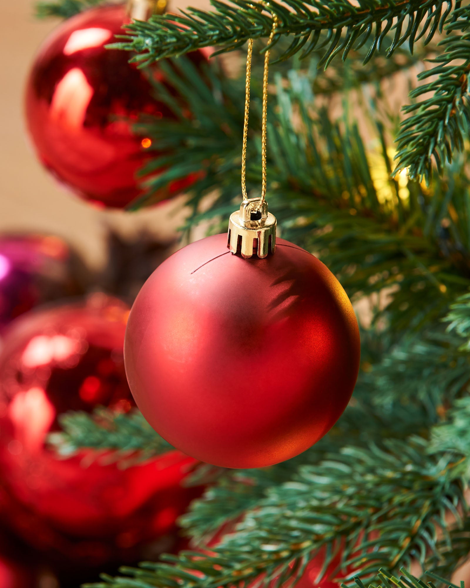 A pre-lit decorated pop-up Christmas tree with red and white baubles and integrated warm white LED lights, standing in a living room setting.