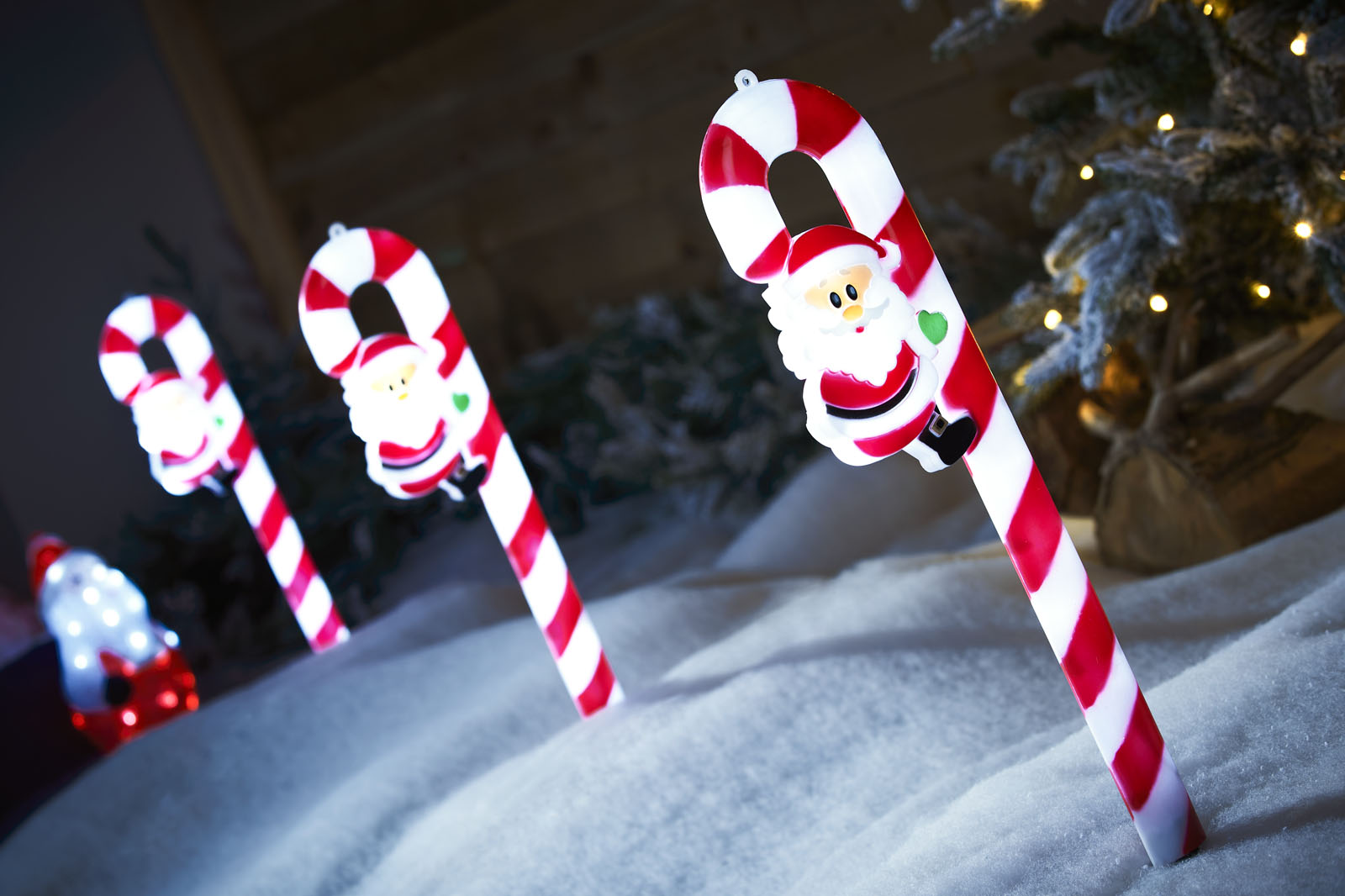 Three red and white Santa Clause candy cane garden stakes at an angle close up
