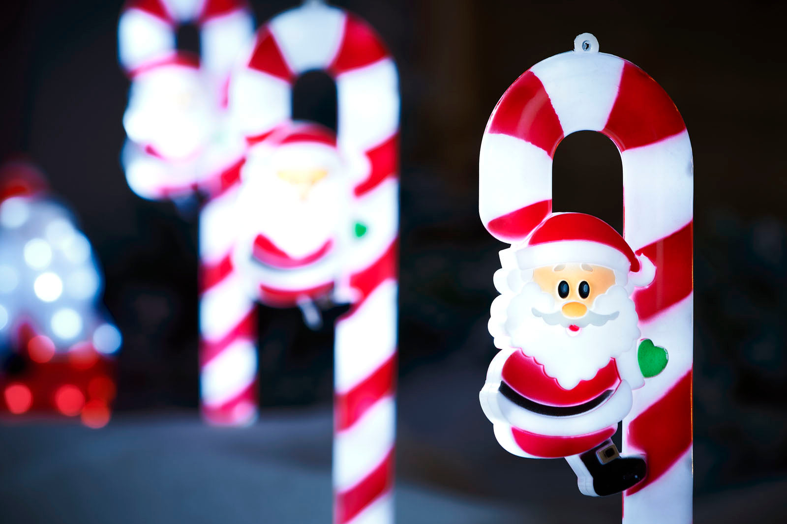 Close up of a red and white Santa Clause Candy cane garden stake with 2 blurry stakes in the background 